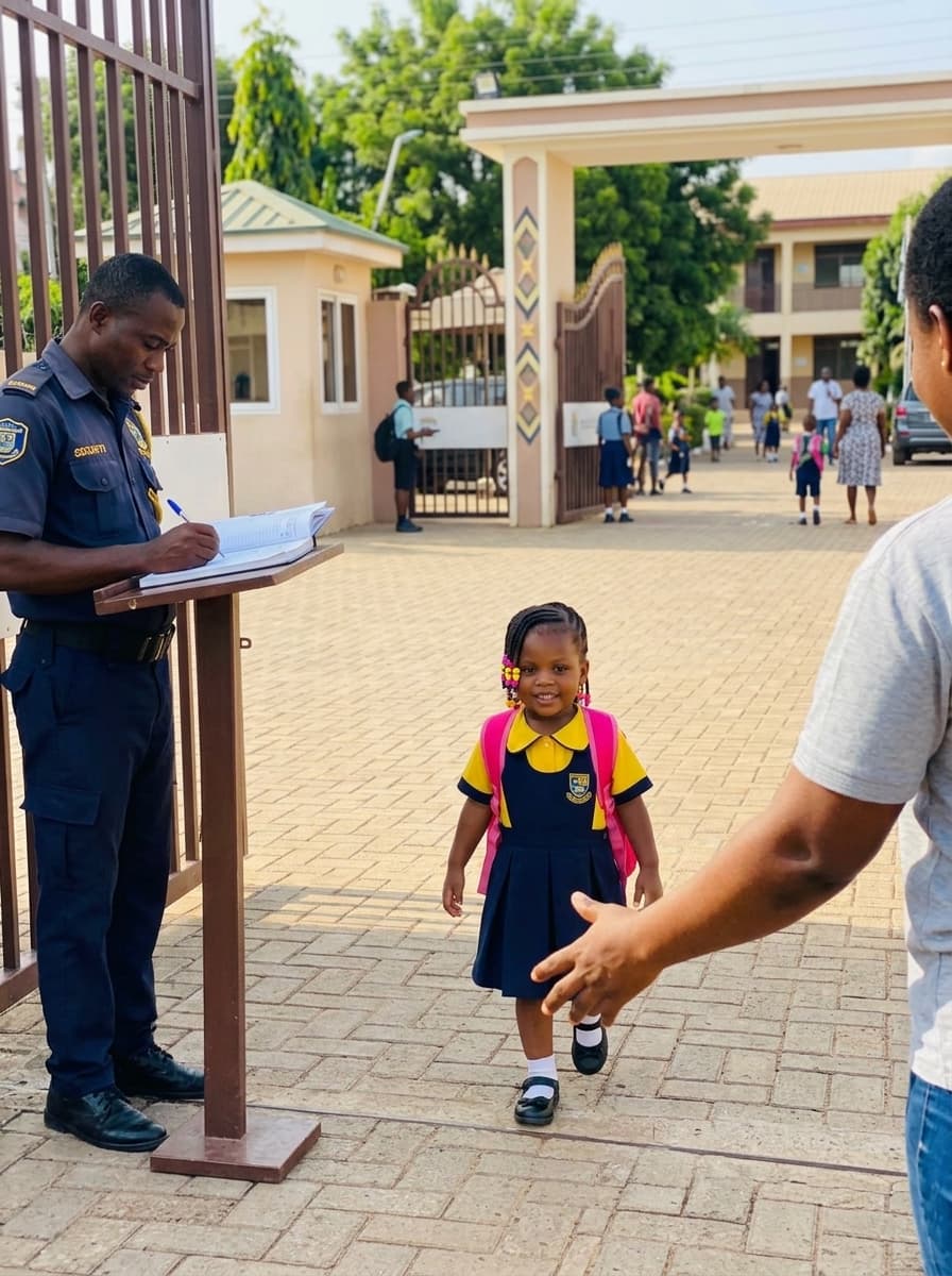 A security guard writing in a paper notebook at a school gate as a student walks toward her waiting parent